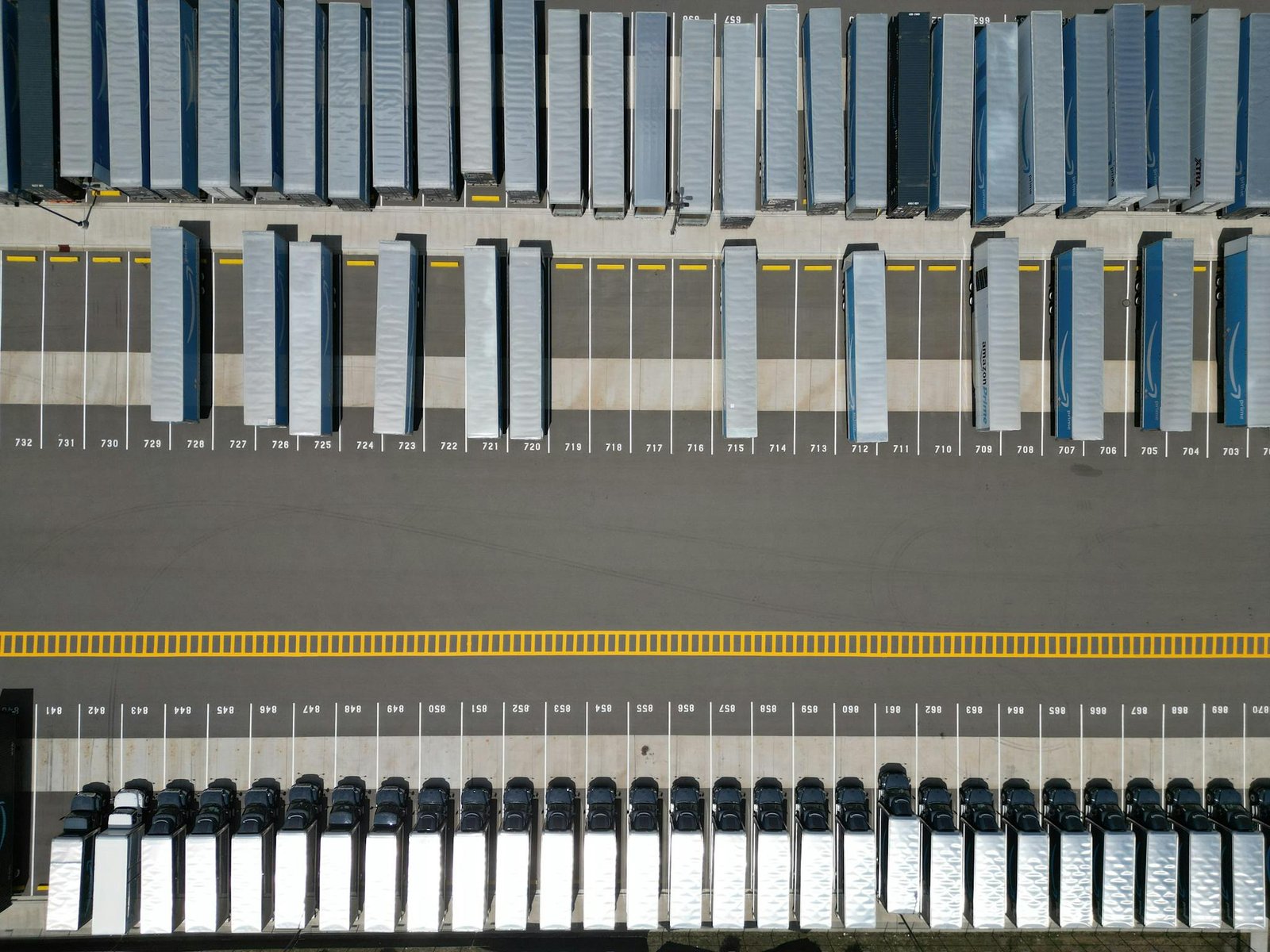 High-angle shot of trucks parked in an organized grid in an industrial parking lot.